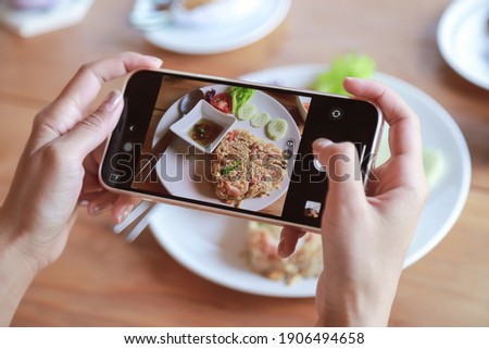 Hand hold smartphone taking photo of fried rice on dish before eating in cafe. people living lifestyle with technology and living life 