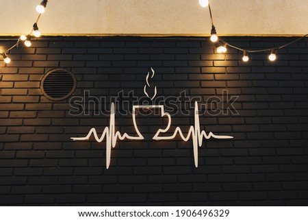 Coffee symbol on black brick wall with garlands