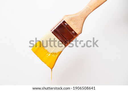 Close-up paintbrush with liquid yellow paint drips off the brush Royalty-Free Stock Photo #1906508641