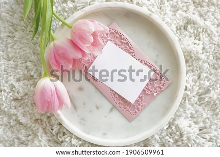 blank greeting cards, invitation mock up and pink tulip flowers on marble tray top view. wedding, birthday, mother's day, Holiday background.Stationery still life with blank paper sheets.copy space