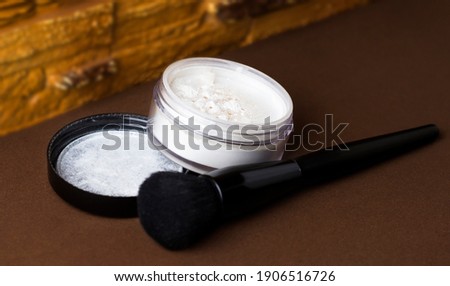 Matte white face powder with a black brush. A jar of powder on a brown background. Royalty-Free Stock Photo #1906516726