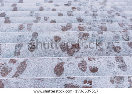 A picture of some footsteps in snow on some stairs outside .