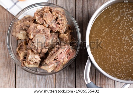 Saucepan with bone broth meat and vegetables cooking ingredients and spices on the table. Top view