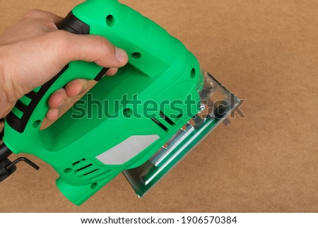 Picture of a green jig saw on a wooden background