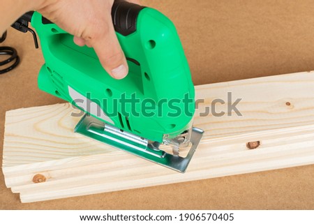 Picture of a green jig saw on a wooden background