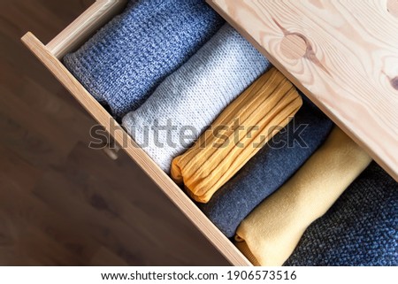 Open wooden dresser drawer with warm knitted woolen clothes. Home vertical storage. Wardrobe organisation. Trendy colors. Royalty-Free Stock Photo #1906573516