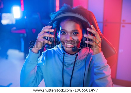 Portrait Streamer African young woman professional gamer playing online games computer, neon color.