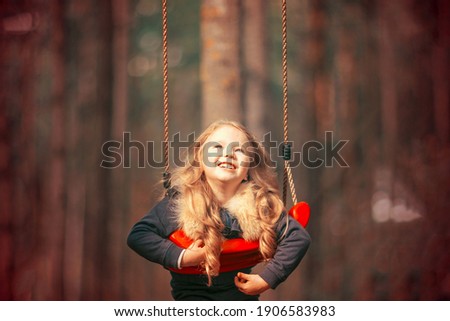 Happy child girl on swing in the park. Little kid playing during the walk