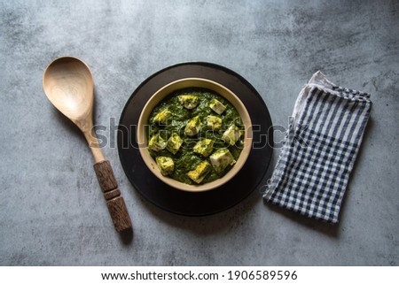 Top view of Palak paneer or cottage cheese cubes in spinach curry with use of selective focus on a particular cottage cheese cube with rest of the cubes and everything else blurred.  Royalty-Free Stock Photo #1906589596