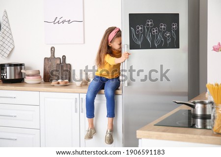 Little girl opening refrigerator in kitchen