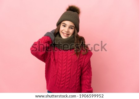 Little girl with winter hat isolated on pink background laughing