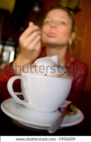 Cappuccino with milk foam,  delighted girl at background