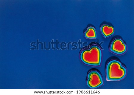 Colorful lgbt Valentine day background - multicolored hearts as decorative border on dark blue backdrop, copy space, top view.