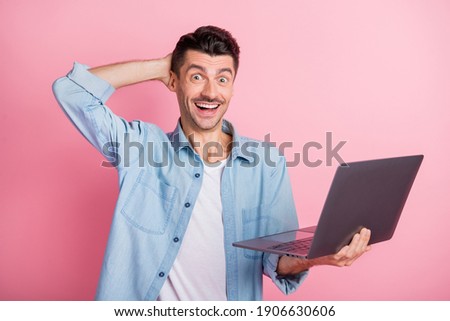Photo portrait amazed surprised programmer keeping laptop staring smiling isolated pastel pink color background