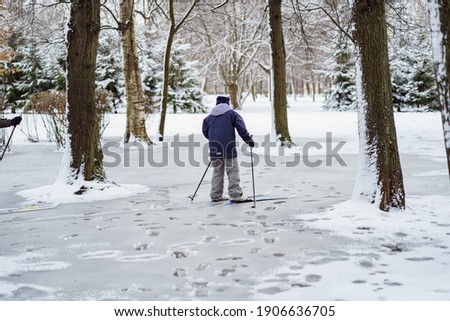 a schoolboy skiing on slushy snow in winter park, having fun