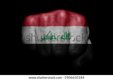 Flag of Iraq painted on strong fist on black background