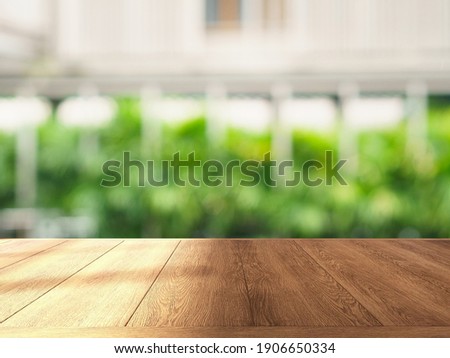Shinny empty natural wooden counter top for product display and beautiful blurred bokeh picture of a green outdoor space or resort in the background. Commercial, Advertising, Healthy living goods.