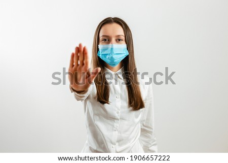 Attractive young woman showing refusal gesture wearing blue face mask isolated on gray background. Stop coronavirus concept