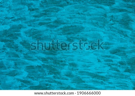 Blue background with a greenish tint from the surface painted with acrylic paints. The surface is painted over with brush strokes. Texture of acrylic paint strokes. Royalty-Free Stock Photo #1906666000