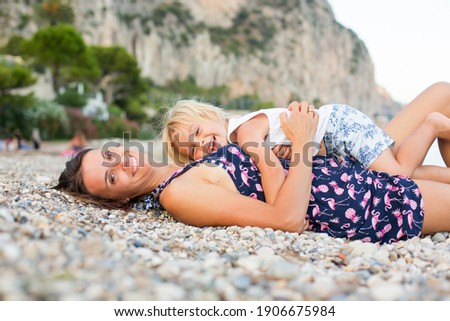 Loving mother and son, blond toddler boy, hugging at the beach, enjoying time together