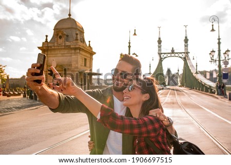 A happy couple taking a selfie in front of the famous liberty bridge during summer in Budapest in Hungary..