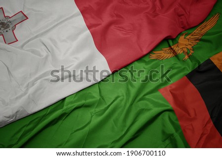 waving colorful flag of zambia and national flag of malta. macro