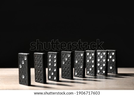 Domino tiles on wooden table against black background. Space for text
