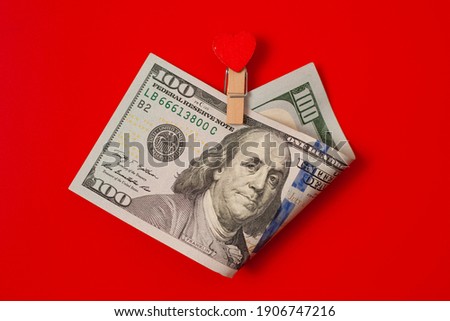 100 with a gift in the form clothespin of a red heart on red table. Valentine's day concept background