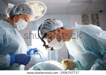 Dental surgery. The surgeon and the assistant. The patient is unrecognizable. Modern dentistry. Photo in the operating room. Concept of healthcare. Royalty-Free Stock Photo #1906747717