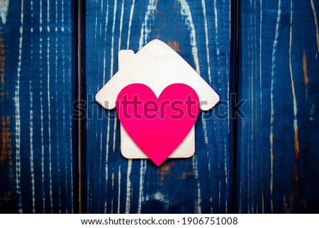 The symbol of the house with heart on wooden background 