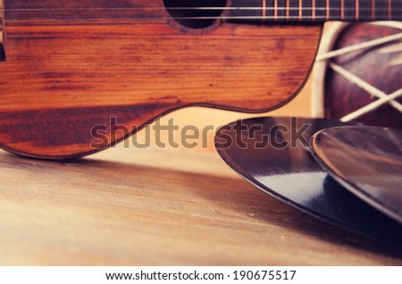 Vintage acoustic guitar and vinyl record on a wooden background