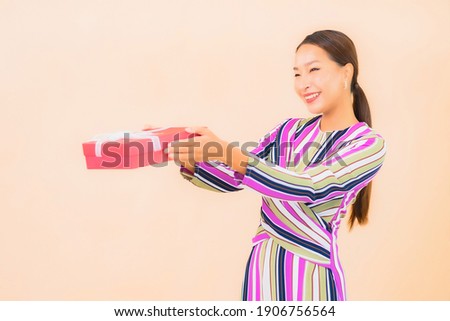 Portrait beautiful young asian woman with red gift box on color background