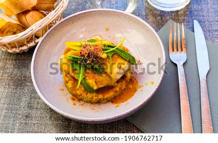 Tasty healthy dinner of baked coalfish fillet with quinoa and curry served with fresh vegetables and greens