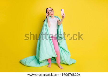 Full length photo of flirty woman dressed nightwear covering duvet making selfie device isolated yellow color background