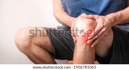 Young man suffering from knee pain at home, close up.  Joint inflammation concept.  Royalty-Free Stock Photo #1906781065