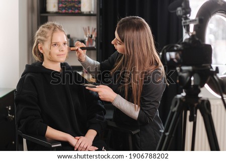 Woman make makeup for attractive blond hair woman in studio. Video of makeup artist applying cosmetics for beautiful model