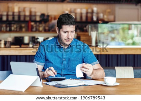 Mature restaurant owner calculating finance and bills of new business – Entrepreneur online using tablet and calculator to work and calculate financial expenses of small coffee shop business start-up Royalty-Free Stock Photo #1906789543
