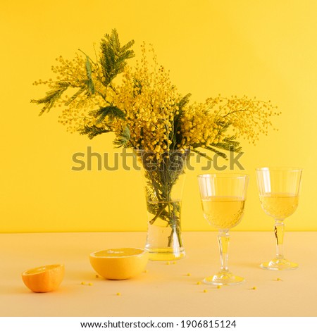 Realistic decorative valentines party with mimosa flower, fresh fruits, lemon and grape and two glasses of wine on yellow background.