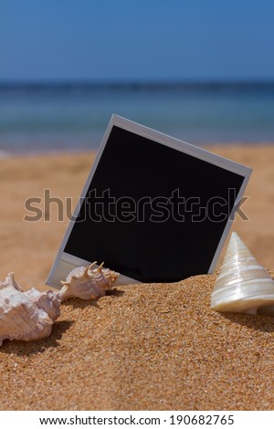blank instant photo with seashels in sand on sea shore