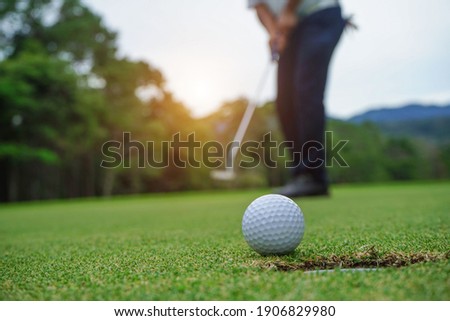 Blurred golfer playing golf in the evening golf course, on sun set evening time. Man playing golf on a golf course in the sun.                                Royalty-Free Stock Photo #1906829980