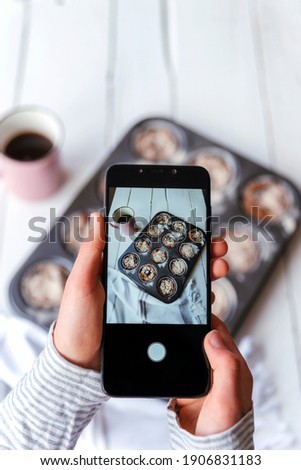 Girl's hands taking pictures of healthy oatmeal cupcakes by phone, top view. Selective focus