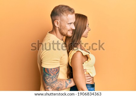 Young couple of girlfriend and boyfriend hugging and standing together looking to side, relax profile pose with natural face and confident smile. 