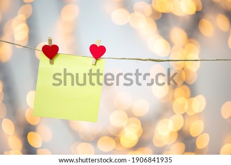 Blank Yellow sticky note hanging with red hearts with bokeh background, romantic Valentines day concept background copy space love