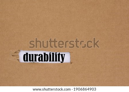 The word durability is written in a hole in the cardboard. Royalty-Free Stock Photo #1906864903