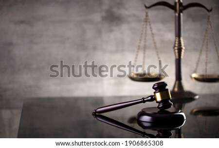Law and justice concept. Mallet of the judge, hourglass, scales of justice. Gray stone background, reflections on the floor. Place for typography. Royalty-Free Stock Photo #1906865308