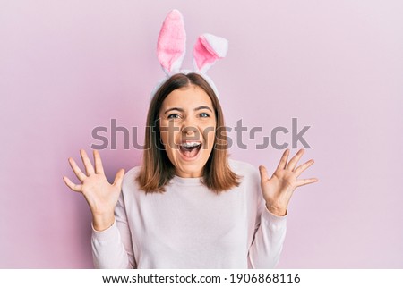 Young beautiful woman wearing cute easter bunny ears celebrating crazy and amazed for success with arms raised and open eyes screaming excited. winner concept 