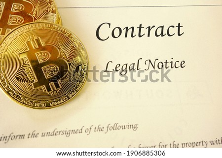 Gold bitcoin cyptocurrency and a legal contract document                               