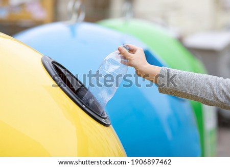 Waste Recycling Concept. Unrecognizable lady throwing plastic bottle into yellow recycle bin container outdoors, sorting garbage, enjoying zero waste living, cropped image with selective focus Royalty-Free Stock Photo #1906897462
