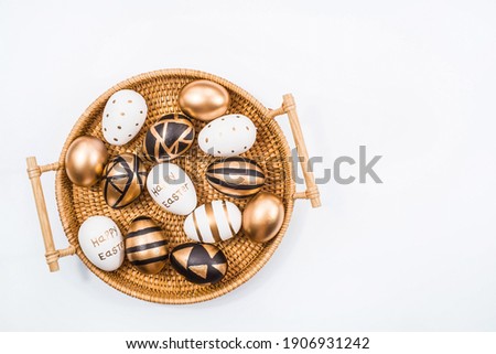 Golden, black, white Easter eggs in a basket on a white background. Geometry. The minimal concept. Top view. Card with a copy of the place for the text.