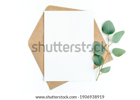 Mockup invitation, blank greeting card and green leaves eucalyptus. Flat lay, top view. Royalty-Free Stock Photo #1906938919